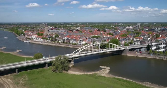 4k Aerial drone shot flying along the Wilhelmina bridge above the river the IJssel showing the sunny skyline of the old Dutch Hanza city Deventer and its landmark church tower of the Lebuinus kerk.