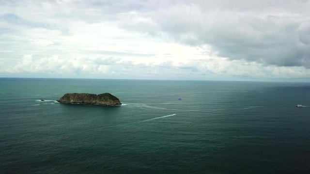 Wide aerial video of island and parasailor off Manual Antonio National Park, Costa Rica.