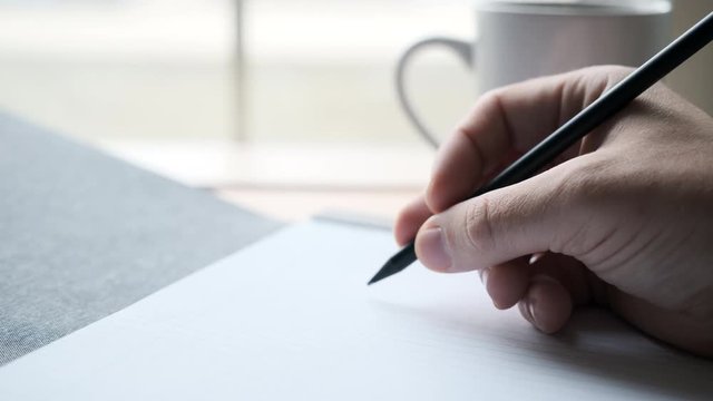 Writer's Block- Male Hand Hesitates while Holding Pencil on Blank Paper in front of Coffee Shop Window as Cars Go By