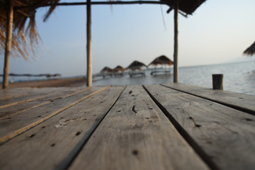 Wooden old table on beach with mountain and cloudy background.