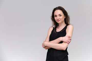 Life is a success. I am pleased with myself. Concept photo of a happy smiling woman satisfied life contented brunette girl in a black T-shirt and jeans on a gray background with flowing hair.