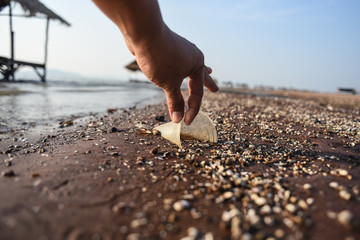 The hands of men are picking up plastic waste from the beach.