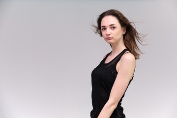 Life is a success. I am pleased with myself. Concept photo of a happy smiling woman satisfied life contented brunette girl in a black T-shirt and jeans on a gray background with flowing hair.