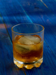 A glass of strong alcohol with ice in a transparent glass