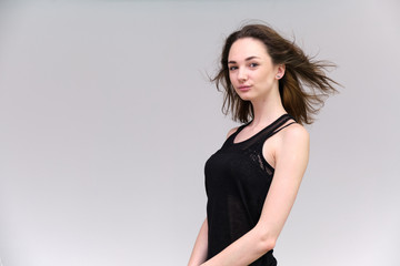 Life is a success. I am pleased with myself. Concept photo of a happy smiling woman satisfied life contented brunette girl in a black T-shirt and jeans on a gray background with flowing hair.