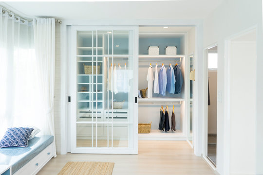 white modern wardrobe with black and blue cloth hanging. 