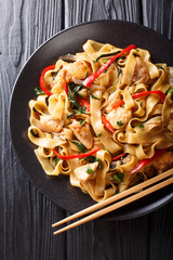 Drunken noodles pad kee mao with chicken, basil, chili pepper and sauce close-up on a plate. Vertical top view © FomaA