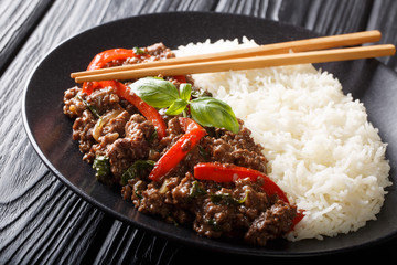 Delicious basil beef with bell peppers, garlic and onions served with rice closeup on a plate. horizontal