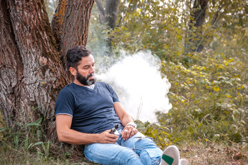 Confident vaper in the fresh air smoking an vape. Non-tobacco smoking.