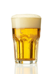 Faceted glass of light beer with foam cap isolated on white