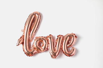 Balloon in the form of inscription love. rose gold color decor on a white background. flat lay