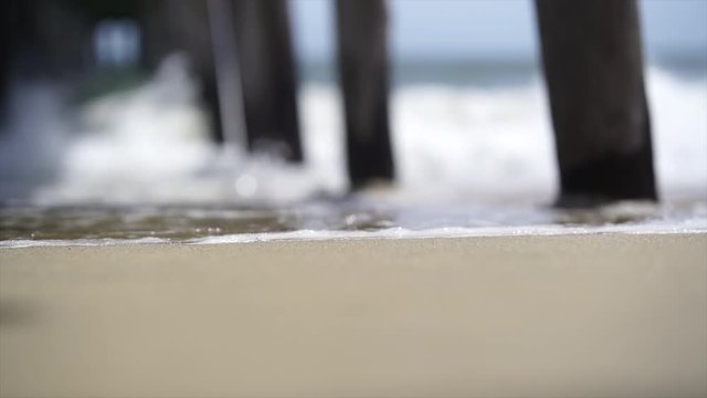 Waves crashing under a pier