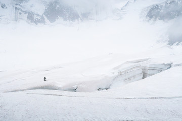 Fototapeta na wymiar Tourist walking on the glacier near the crack. View to the Mensu glacier. Belukha Mountain area. Altai, Russia.