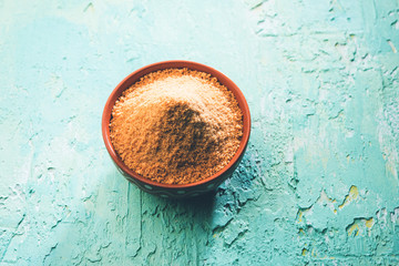 Organic Gur or Jggery Powder is unrefined sugar obtained from concentrated sugarcane juice. served in a bowl. selective focus