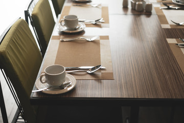 Empty restaurant part of hotel with table and armchair near windows.