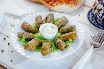 Dolma - rolls made from grape leaves and meat, on white plate. - 270143932