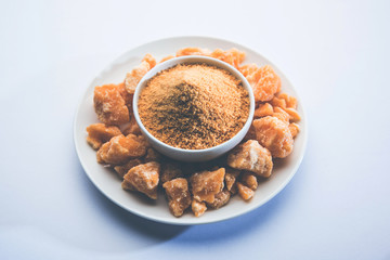 Organic Gur or Jggery Powder is unrefined sugar obtained from concentrated sugarcane juice. served in a bowl. selective focus