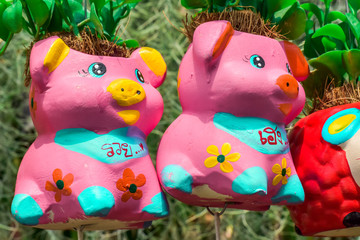 Pink pig shaped ceramic pots hanging in tree store