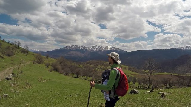 Father carries his infant son in a baby carrier, hiking in the mountains, Dilijan National Park, Armenia.