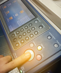 Hand press button on panel of printer, Finger pressing the start button on a multifunction printer.