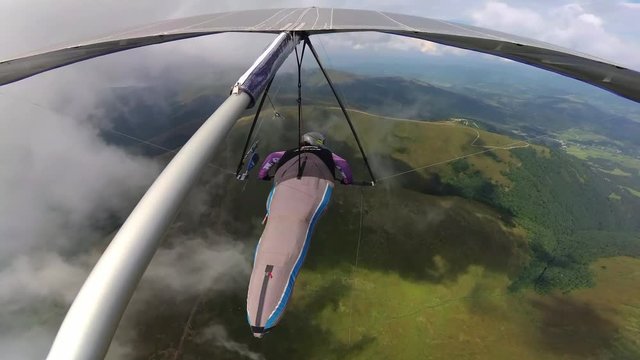 Hang glider pilot fly along the mountain ridge between clouds. Video of extreme sport taken with action camera