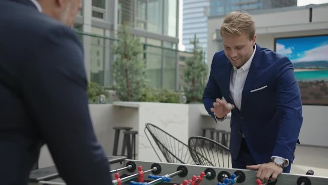 Two business partners have a leisure time together and play table football outside of office. 