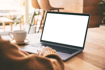 Foto op Canvas Mockup image of a woman's hand using and touching on laptop touchpad with blank white desktop screen with coffee cup on wooden table © Farknot Architect