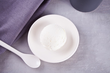 Fototapeta na wymiar Ice cream on a white ceramic plate with gray napkin and gray mug on a gray table
