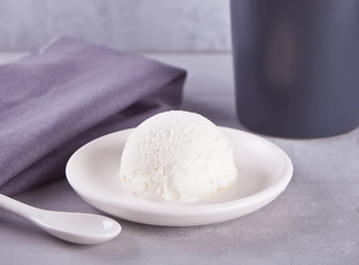 Ice cream on a white ceramic plate with gray napkin and gray mug on a gray table
