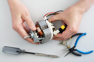 Old elderly home craftsman repairs the electric motor from  mincer