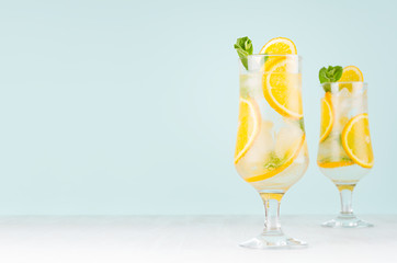 Fresh cold alcohol drink with orange liquor, slices fruit, ice, mint on elegant green color background and white wood board.