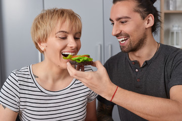 Man feeding wife with sandwich in morning