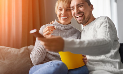 Cheerful couple eating popcorn and watching TV
