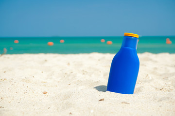 blue sun block bottle on the beach sand