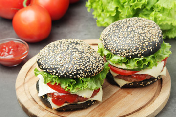Two black burgers with vegetables and beef meat