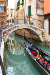 Fototapeta na wymiar Traditional Venetian gondola on canal near bridge in Venice, Italy.