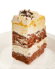A piece of sweet fresh cake with yellow and chocolate cream on a plate on a white background