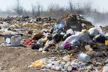 Plastic bags and bottles in a landfill. Unauthorized release of garbage, pollution of nature. The concept of environmental disaster.