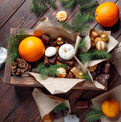 Delicious sweets, chocolates, cookies and oranges for gifts in  wooden box on  vintage table