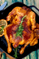 Baked whole chicken with apples in pan on wooden rustic background. Served on wooden board. Christmas chicken..