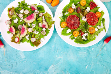 Mix salads on blue background. Fresh Citrus Salad with arugula feta, chia, kumquat and blood...