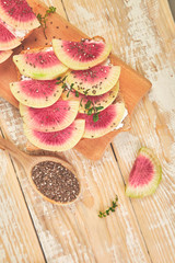Healthy breakfast toasts from sliced watermelon radish or chinese daikon, chia and cottage cheese on board wooden background. Top view. Flat lay. Copy space.