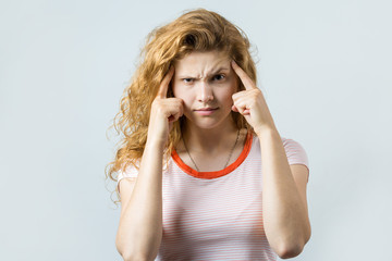 Emotional portrait of a red-haired girl on a gray background, stormy emotions, business concept.	