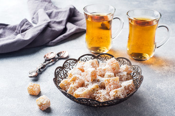 Turkish delight with hazelnut in carved metal bowl and tea in glass Cup, selective focus