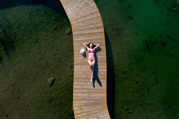 Woman in swimsuit sunbathing on the pier