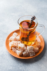 Turkish delight with hazelnut in carved metal bowl and tea in glass Cup, selective focus