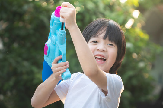 Cute Asian Child Playing With Water Gun In The Summer