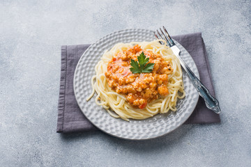 Spaghetti pasta Bolognese on white plate, gray table