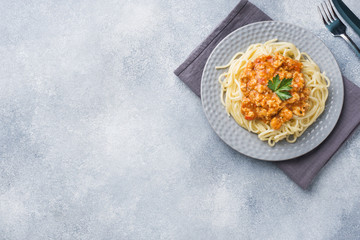Spaghetti pasta Bolognese on white plate, gray table