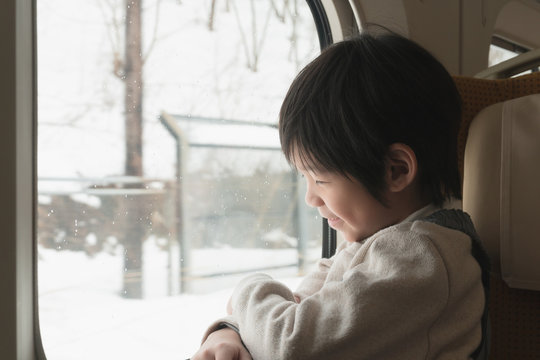 Asian child  looking out train window outside